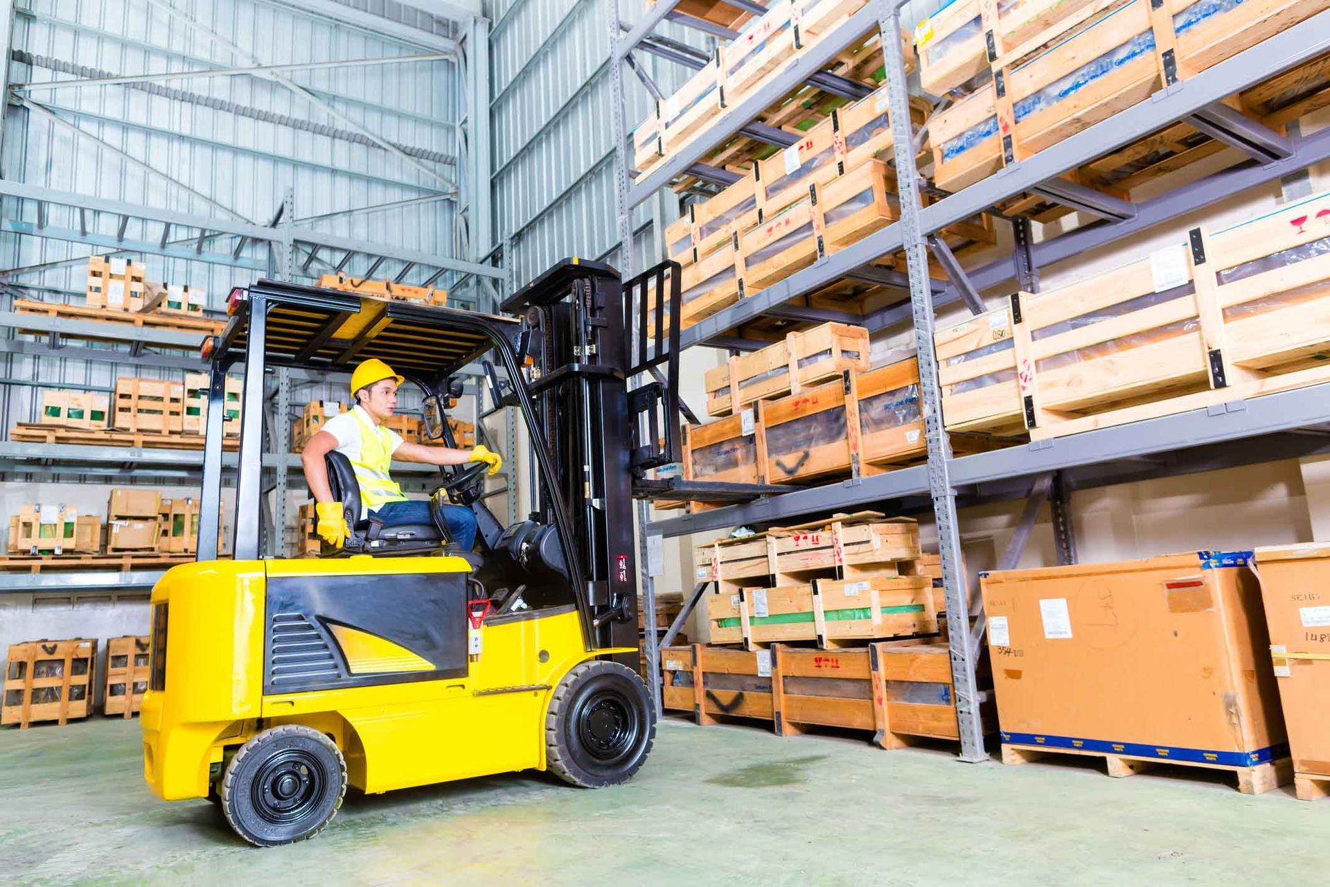 A man is driving a forklift in a warehouse.