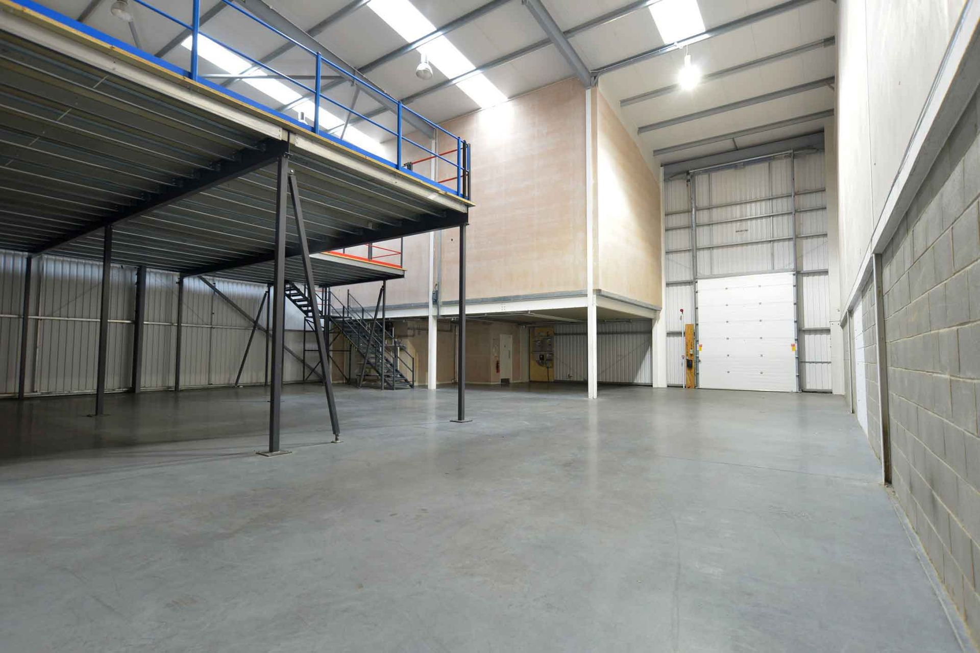 An empty warehouse with a mezzanine floor and stairs.