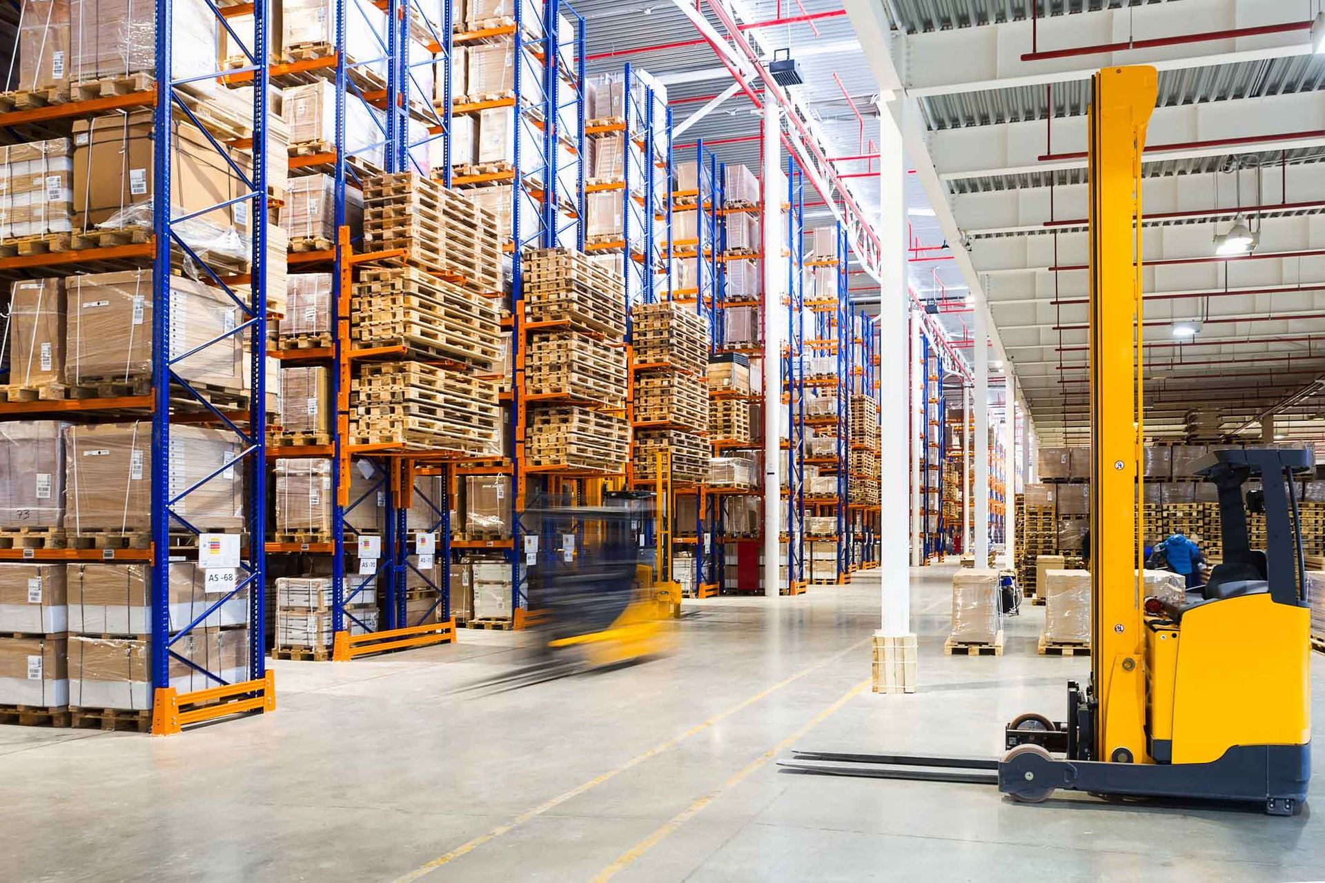 A yellow forklift is driving through a large warehouse.