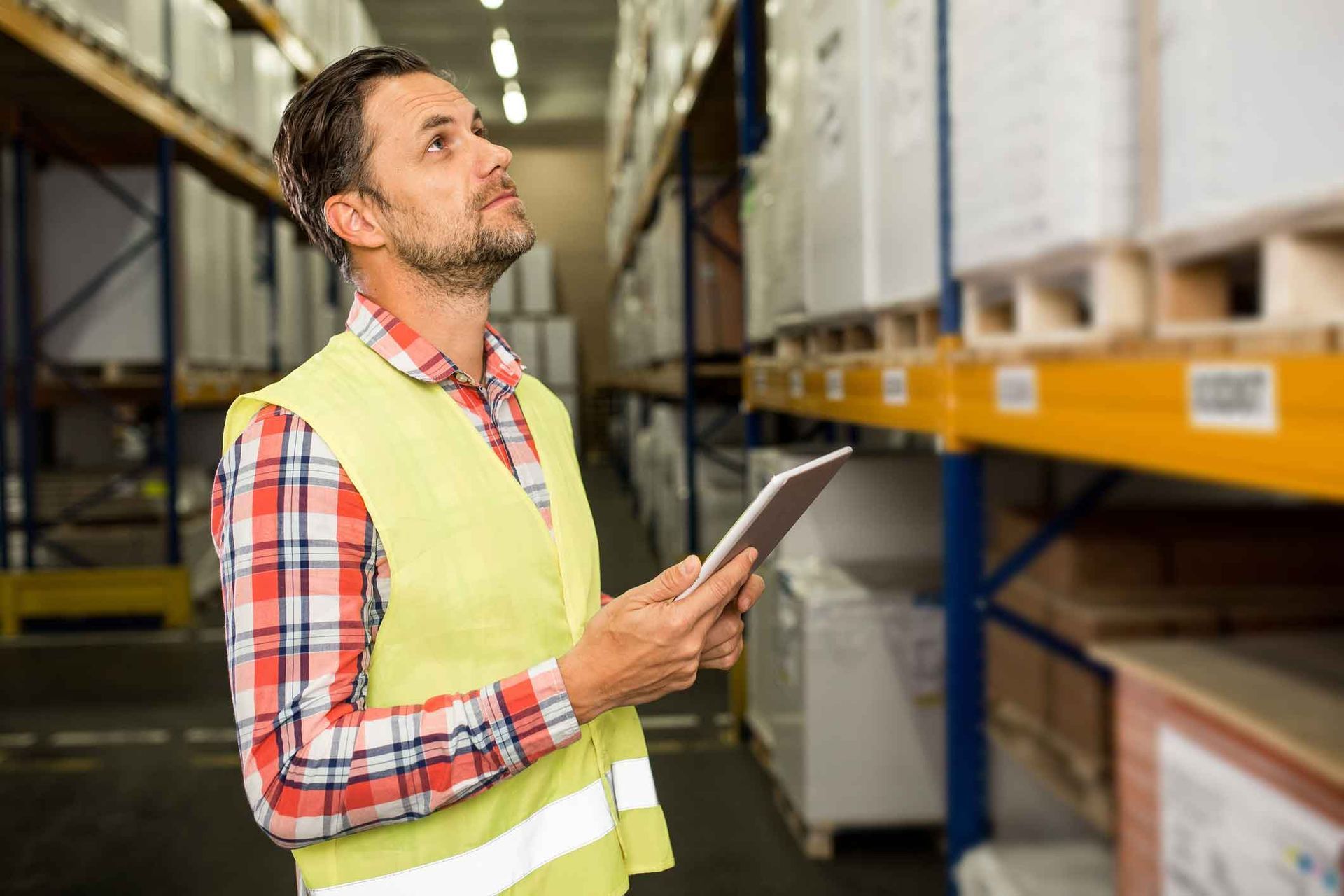 A man is using a tablet in a warehouse.