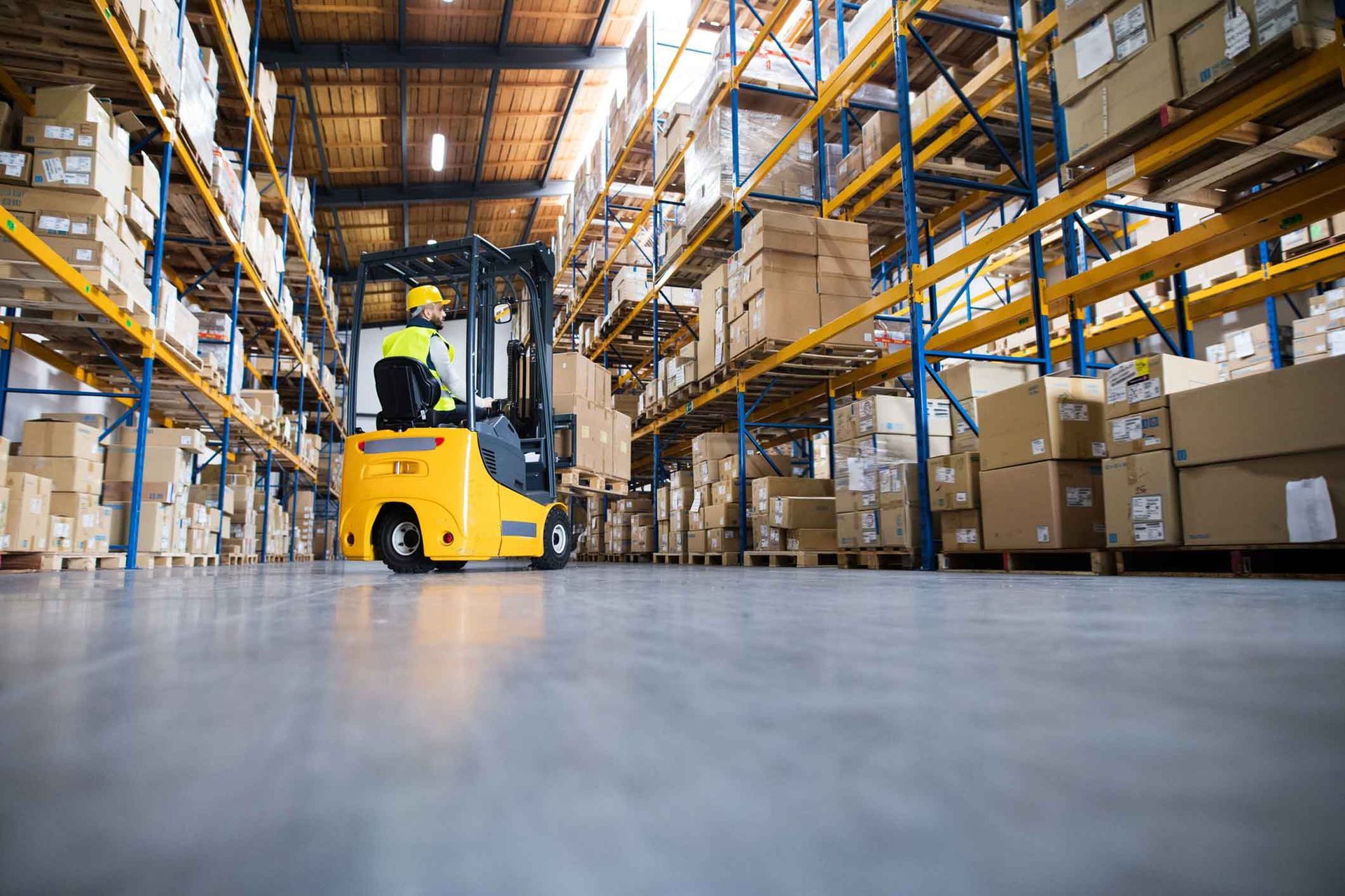 A man is driving a forklift in a large warehouse.