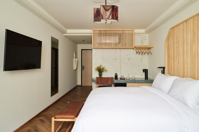 Una habitación de hotel con cama, TV, escritorio y detalles de madera.