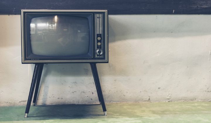 An old television is sitting on a stand in front of a wall.