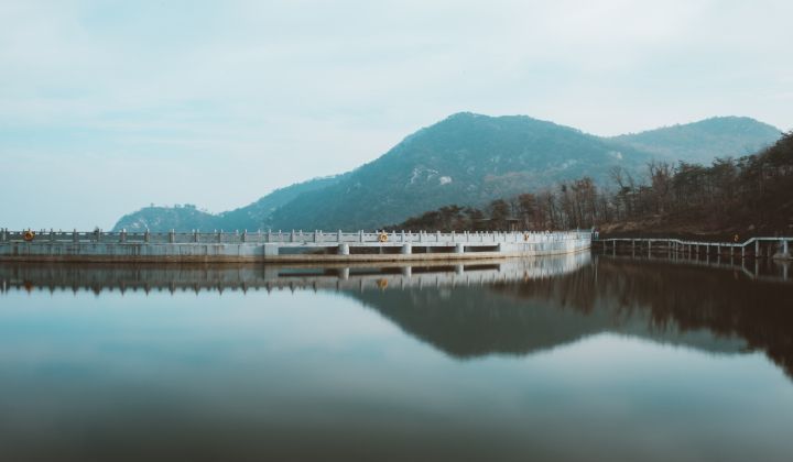 There is a bridge over a lake with mountains in the background.