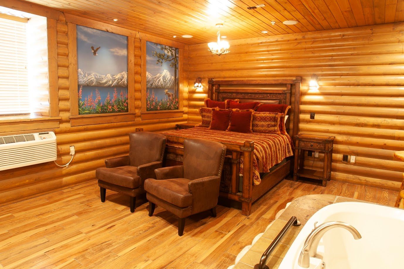 A log cabin bedroom with a king size bed , chairs , and a jacuzzi tub.