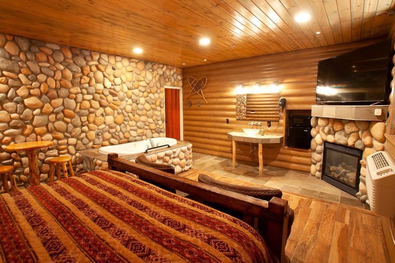 A bedroom with a stone wall and a fireplace