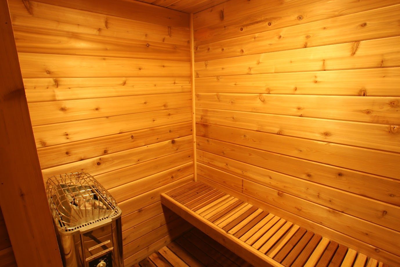 A small wooden sauna with a bench and heater.