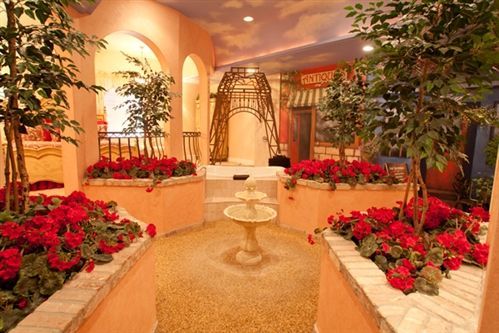 A fountain in the middle of a garden with red flowers