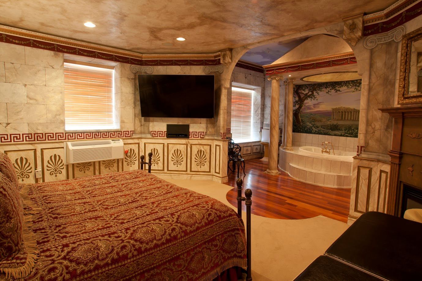 A bedroom with a large bed , television , fireplace and bathtub.