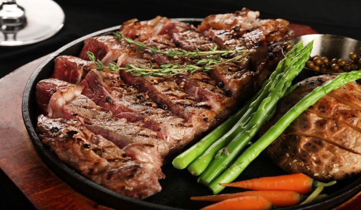 A pan filled with steak , asparagus , carrots and mushrooms.