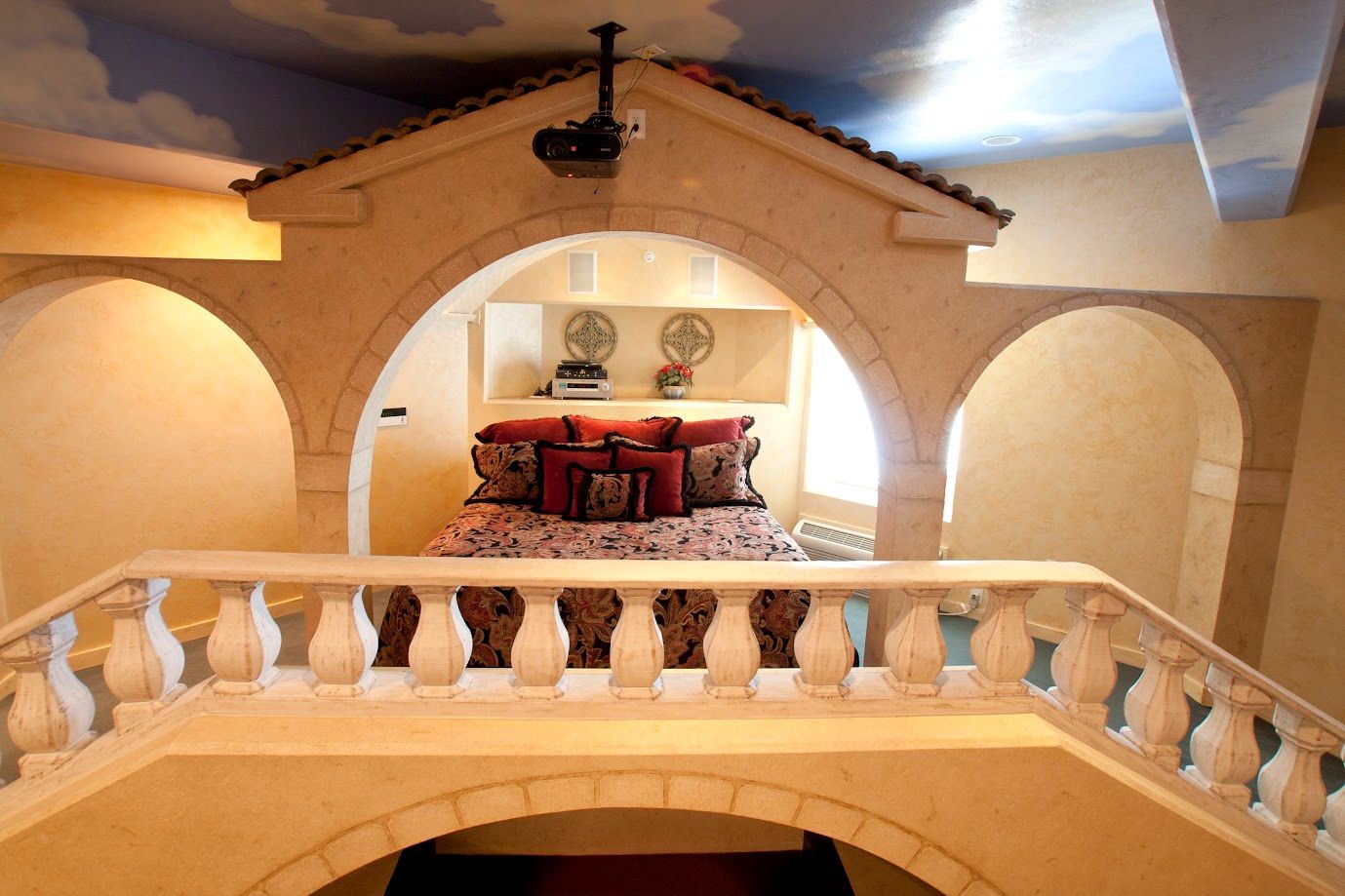 A bedroom with a balcony and a projector on the ceiling