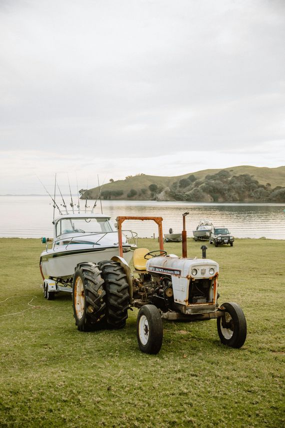 A tractor is pulling a boat on a trailer in a grassy field.