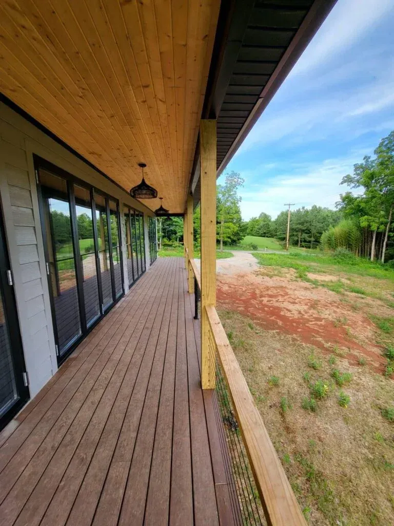 A large wooden porch with a lot of windows and a ceiling fan.
