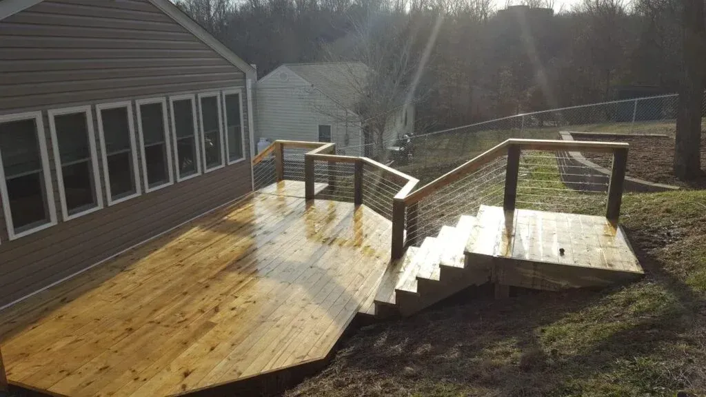 A wooden deck with stairs leading up to a house.