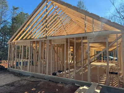 A house is being built with wooden beams and a roof.