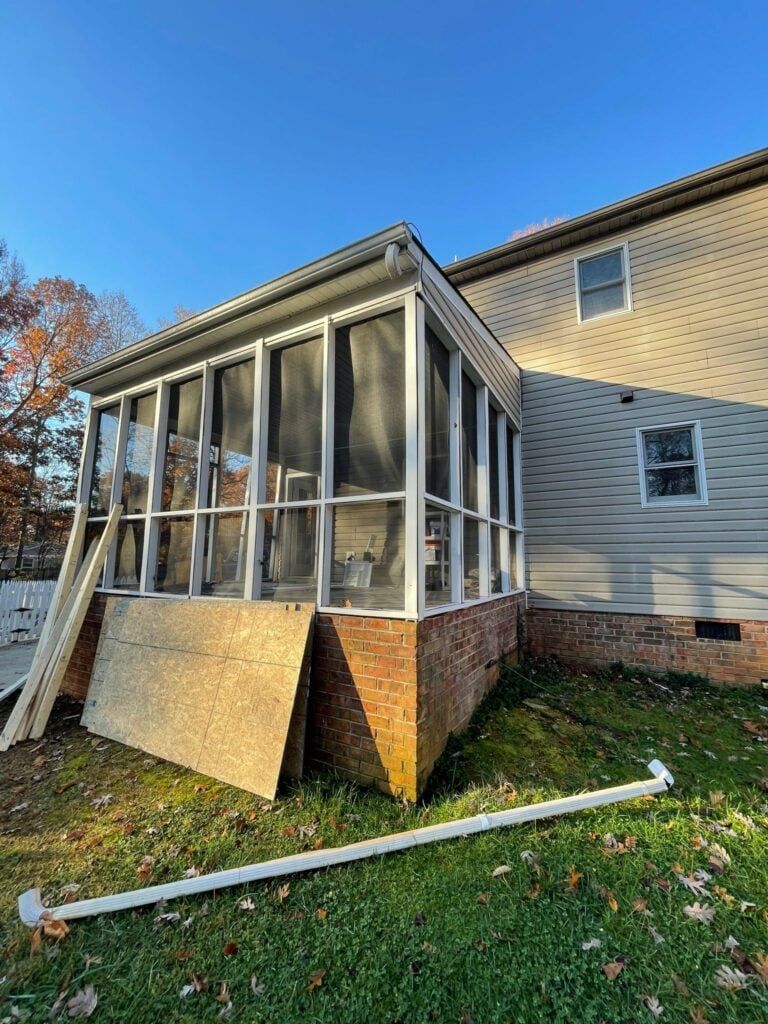 A screened in porch is being built on the side of a house.