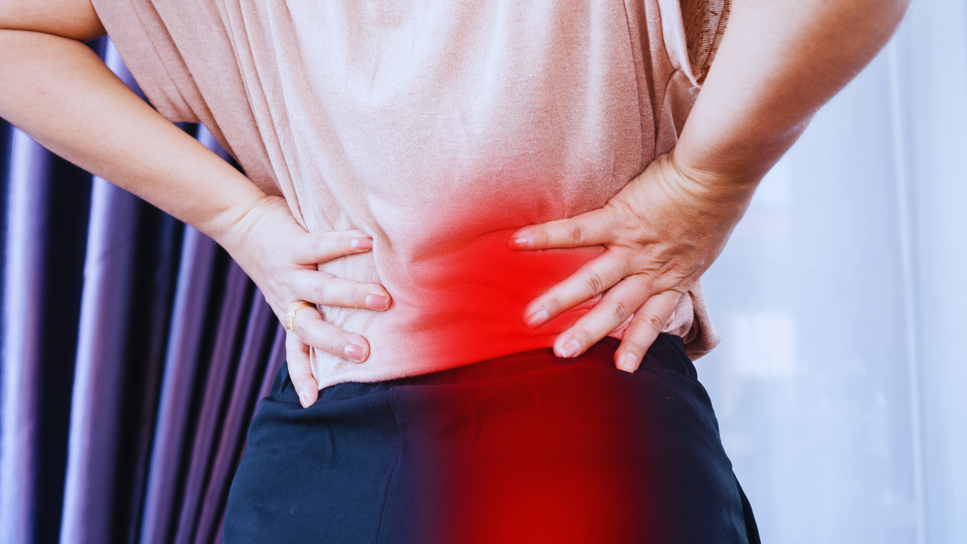 Person with hands on lower back, indicating pain, highlighted in red.