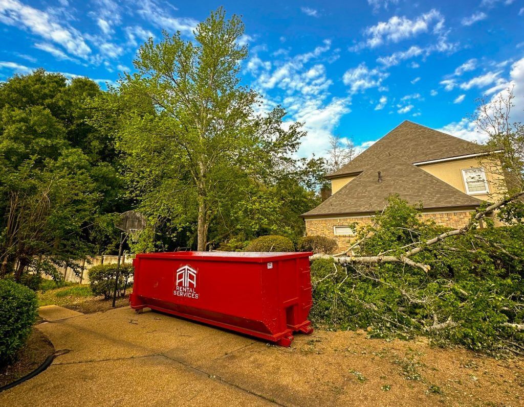 A red dumpster is parked in front of a house.