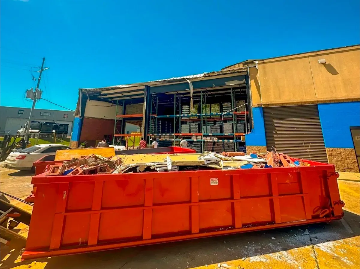 A large red dumpster is parked in front of a building.