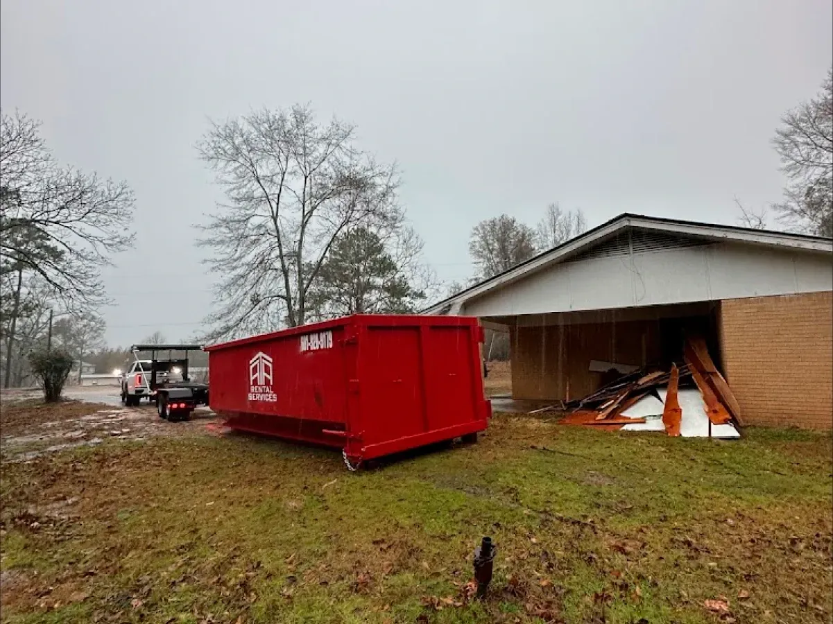 A red dumpster is parked in front of a house.