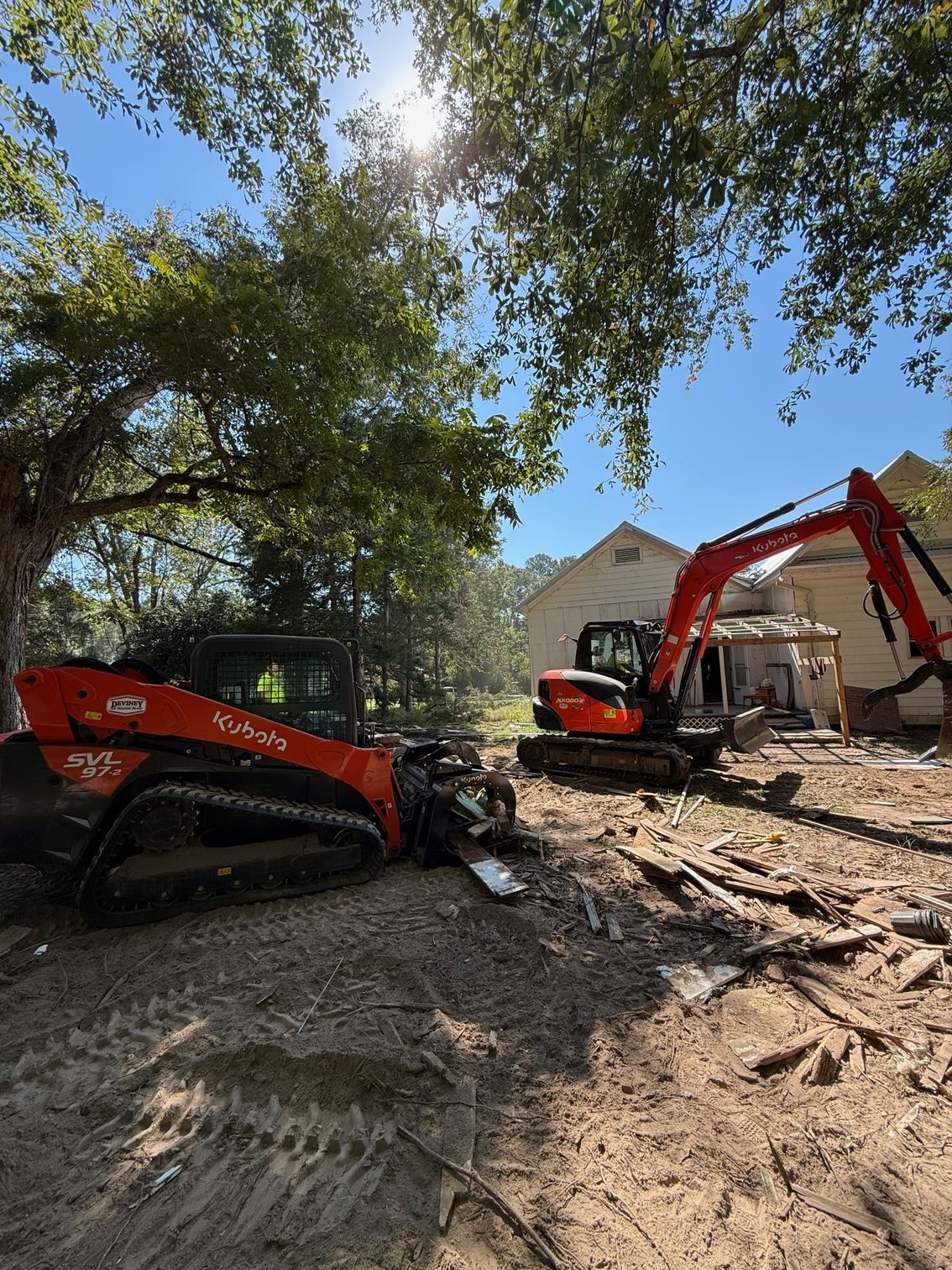 A bulldozer and an excavator are parked in front of a house.