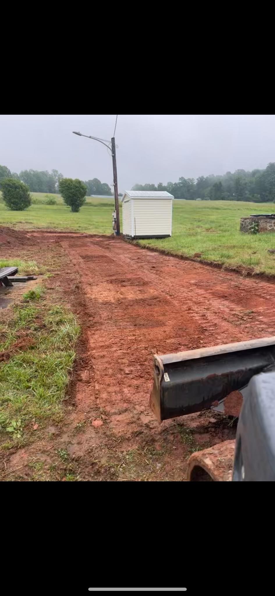 Dirt path through a grassy field leading to a white utility box under a cloudy sky