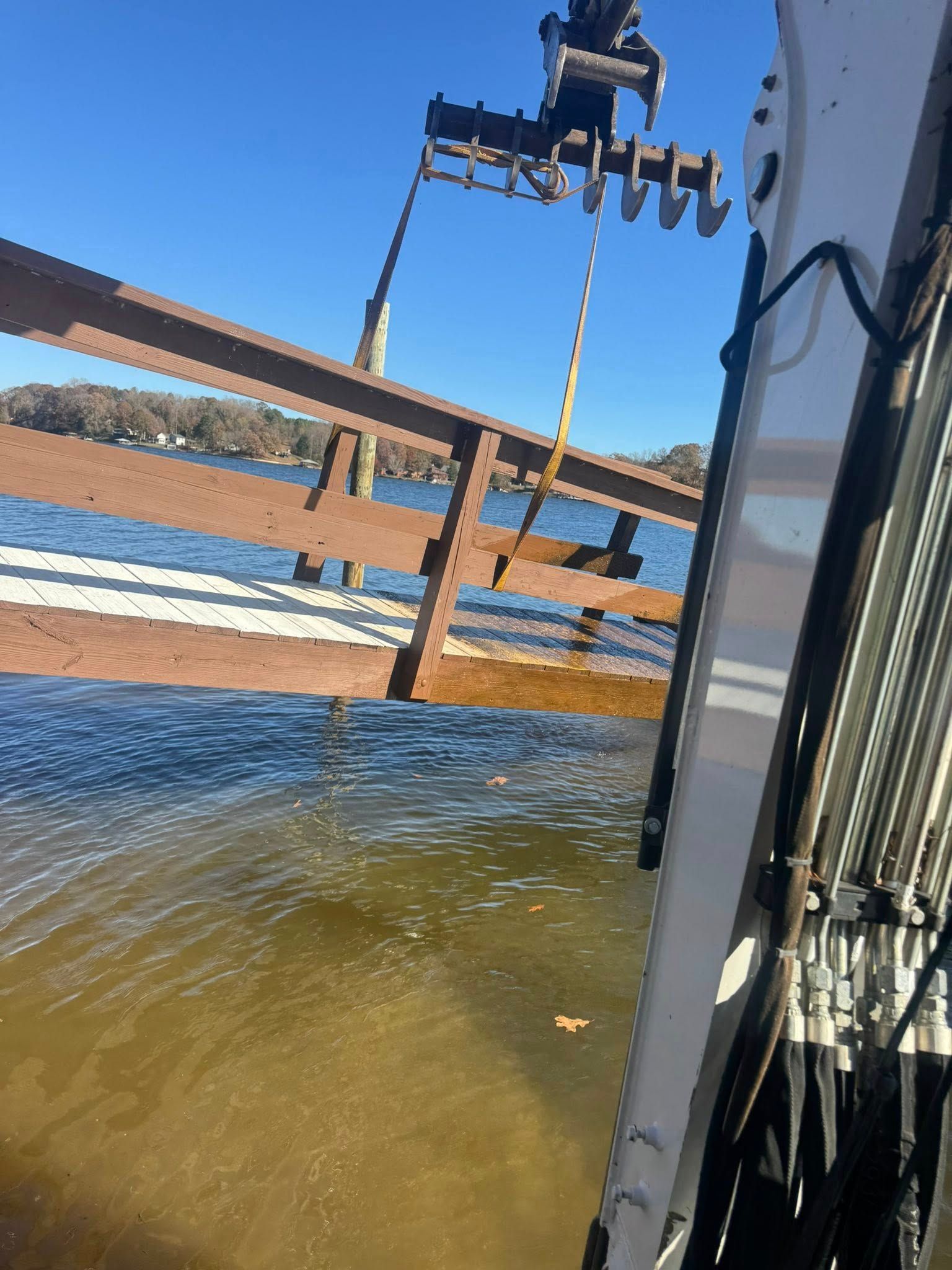 Shoreline water with a wooden railing and a mounted sensor under a clear blue sky
