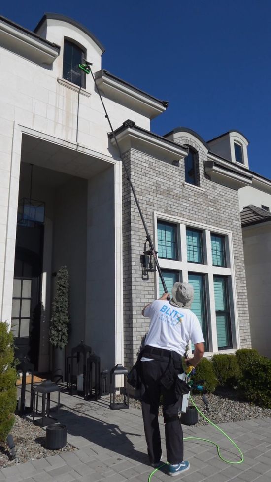 Person wearing pink gloves cleaning a window with spray bottle and squeegee.