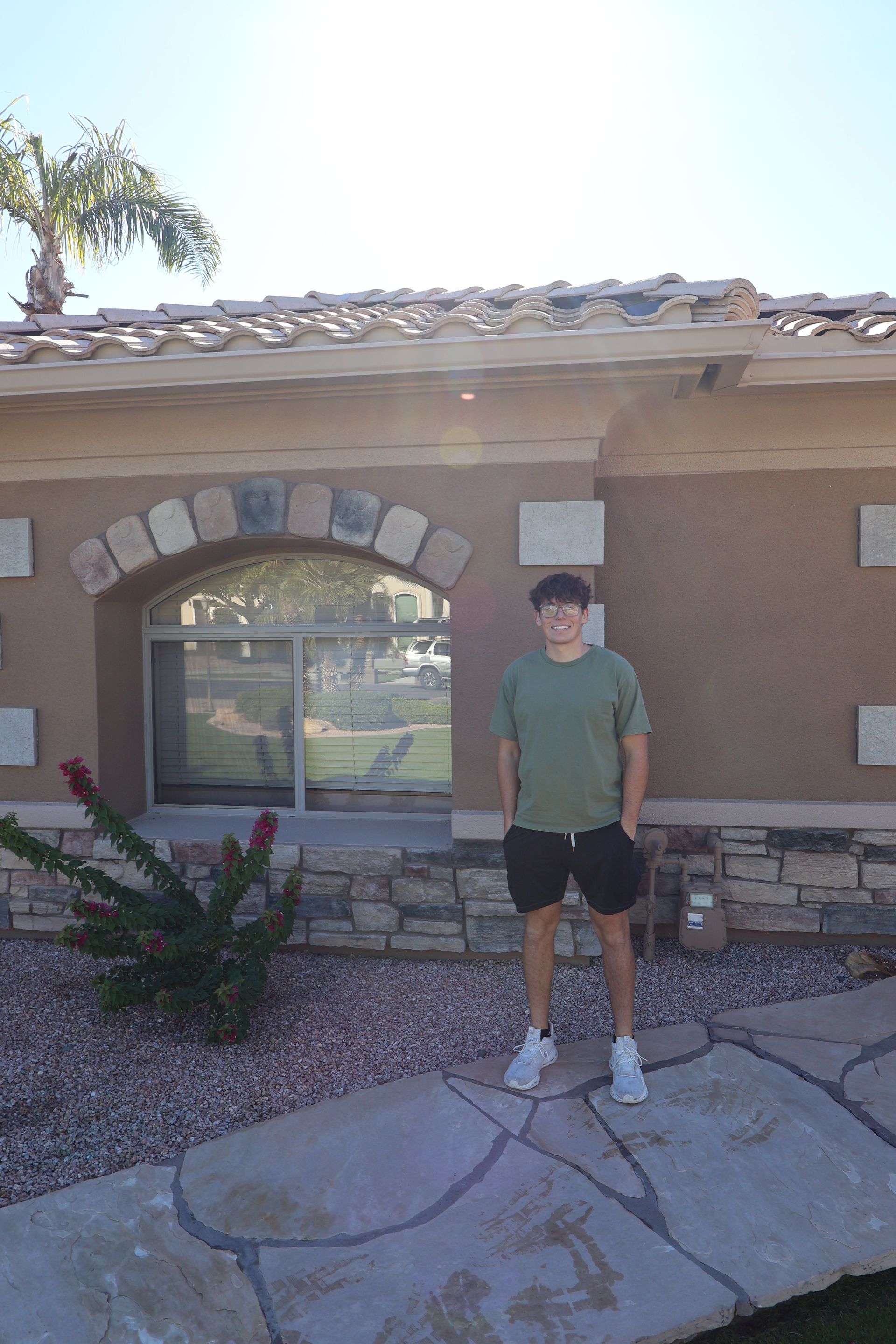 Woman spraying a window with a spray bottle, cleaning inside near a sheer curtain.