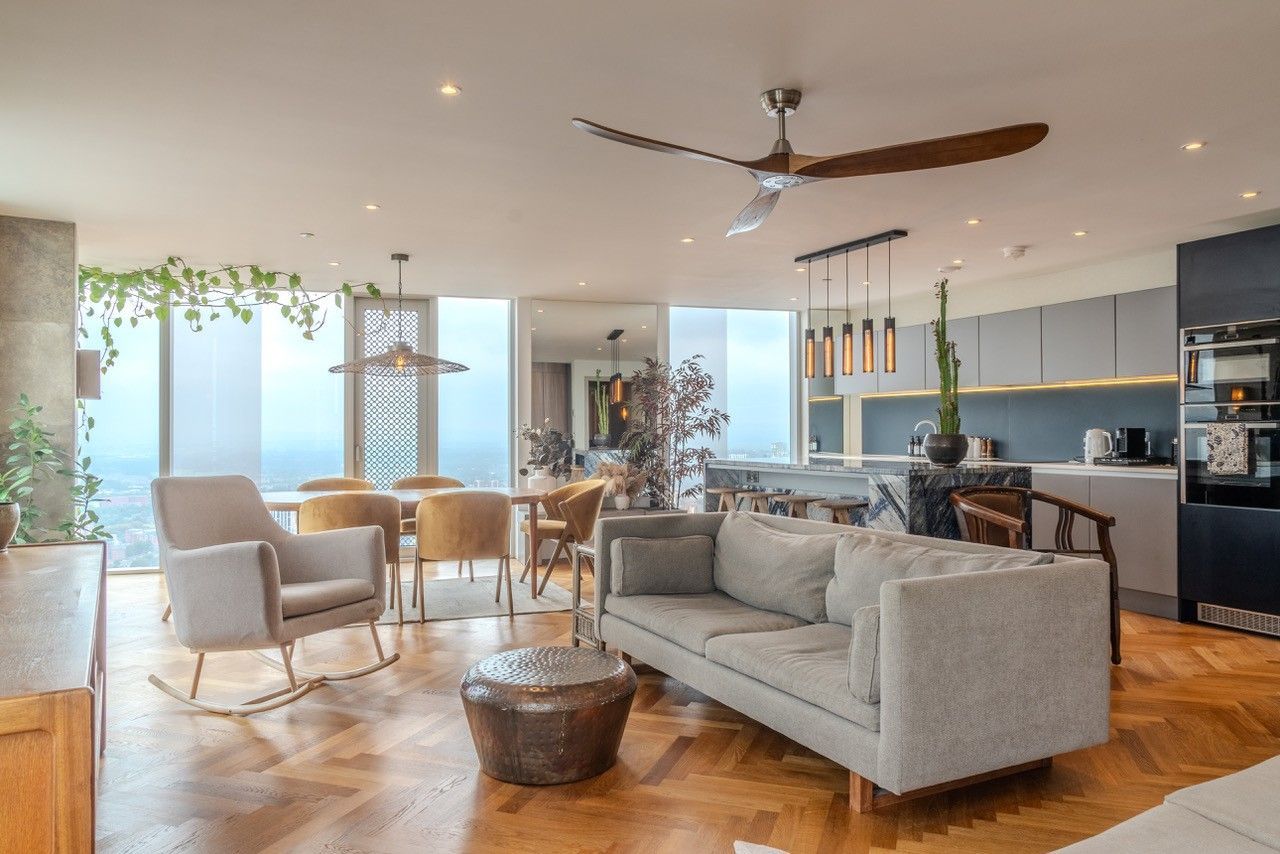 Spacious modern apartment with a living area, dining table, and kitchen. Large windows offer a city view.