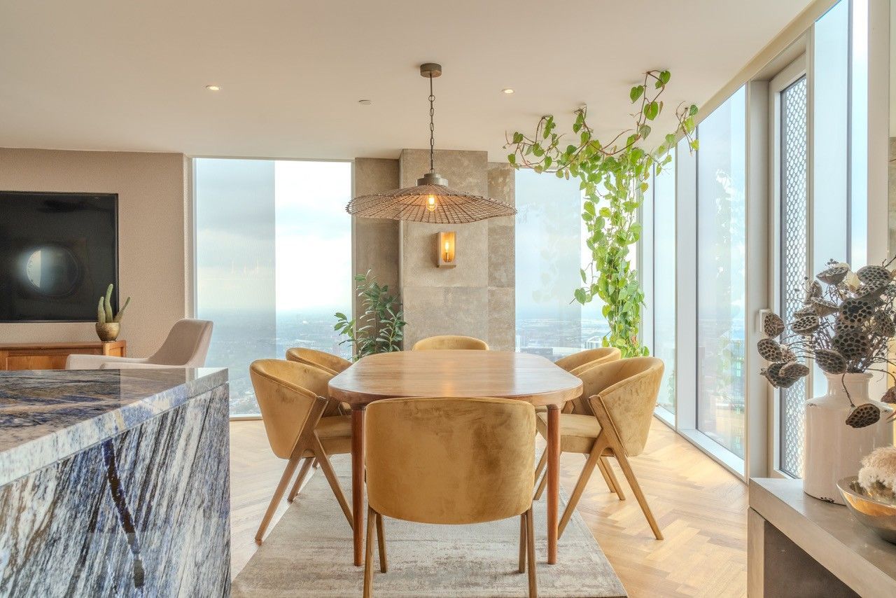 Dining area with light wood table, yellow chairs, and natural light from large windows.