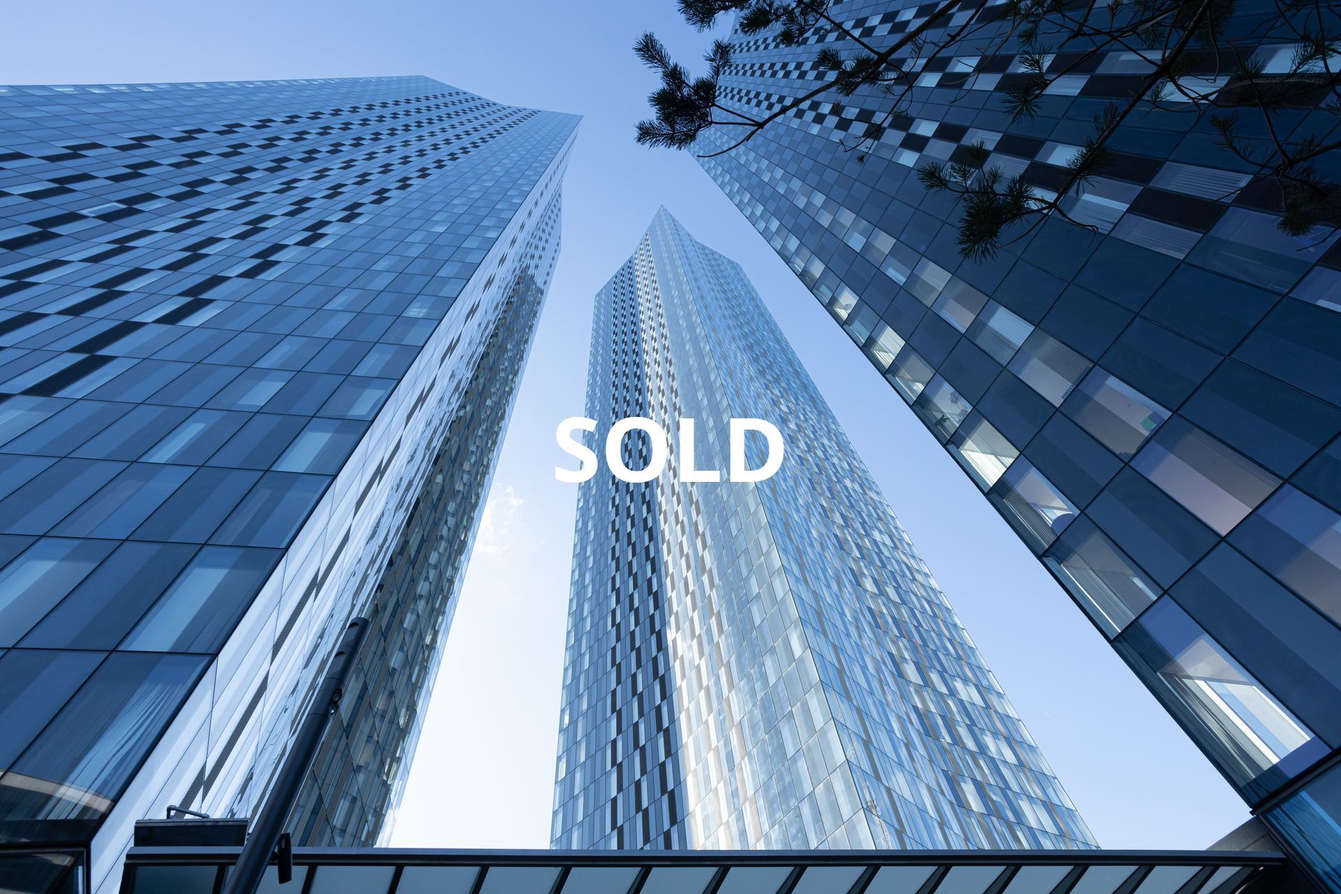 Three tall glass skyscrapers against a blue sky, with 