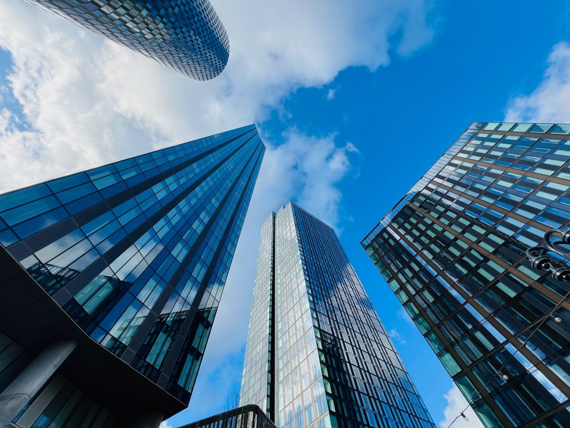 Skyscrapers against a bright blue sky with scattered clouds.