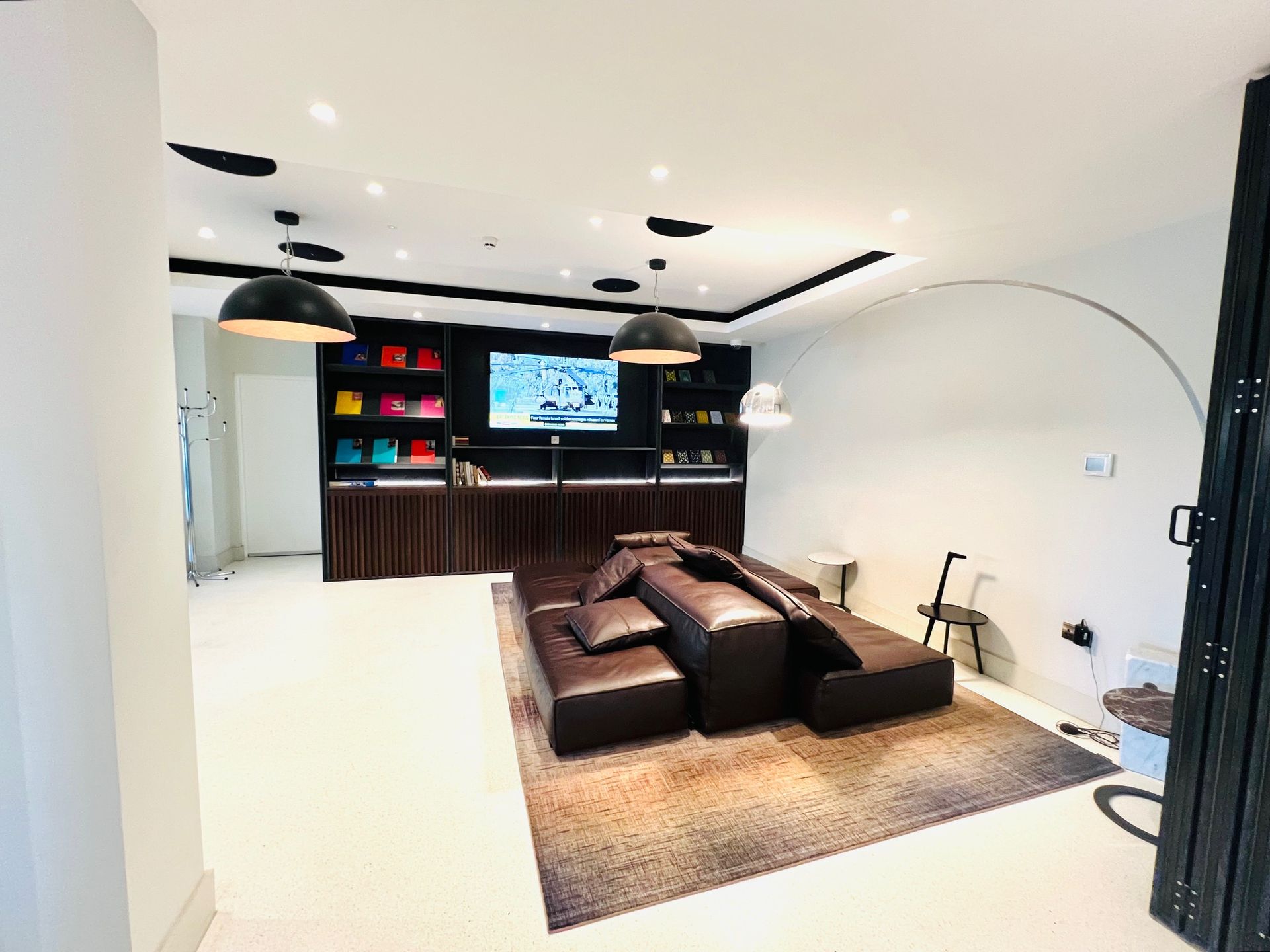 Luxury store interior with display shelves, TV, and brown leather seating on a rug.