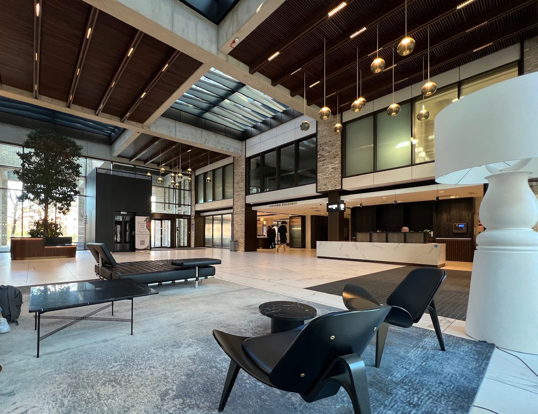 Modern lobby with seating area, reception desk, and tall windows.