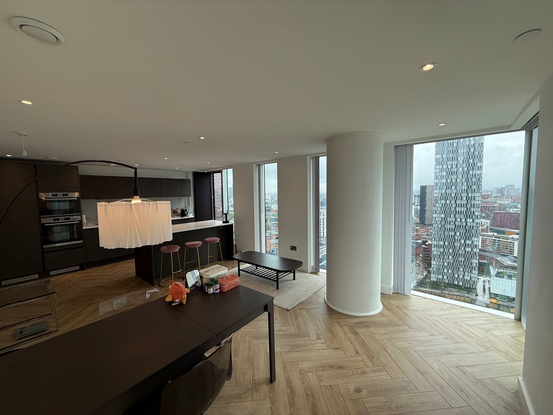 Modern apartment interior with city view. Kitchen and dining areas with light wooden floors.