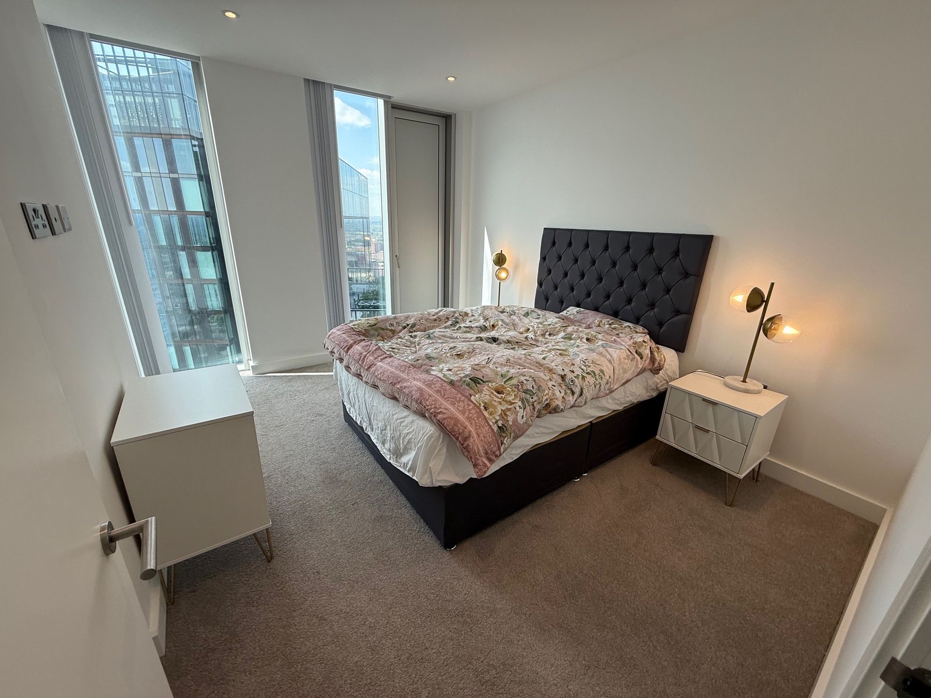 Bedroom with a bed, nightstands, and a window with a city view.