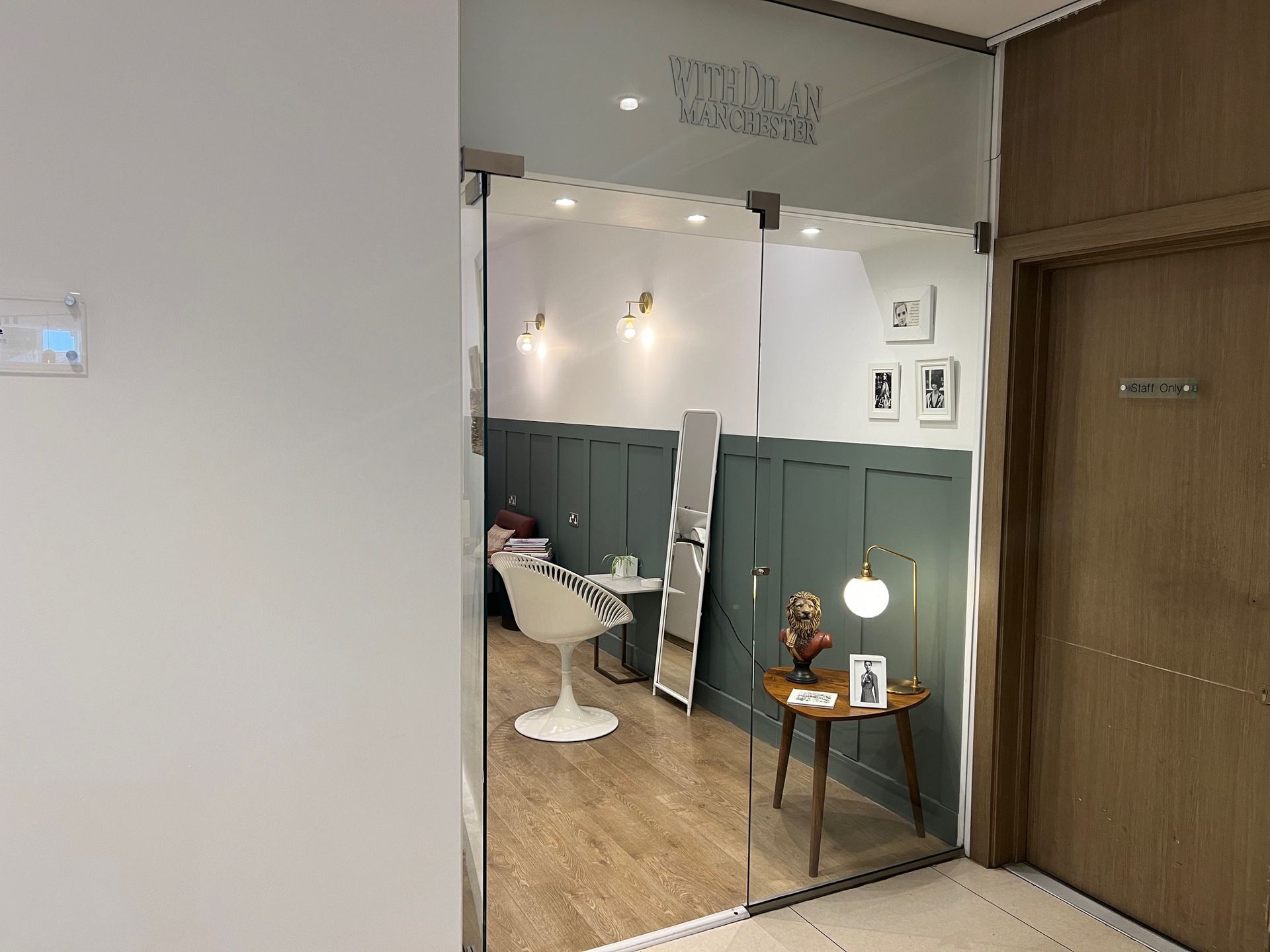 Interior of a beauty salon with glass doors, white walls, and a green accent wall.
