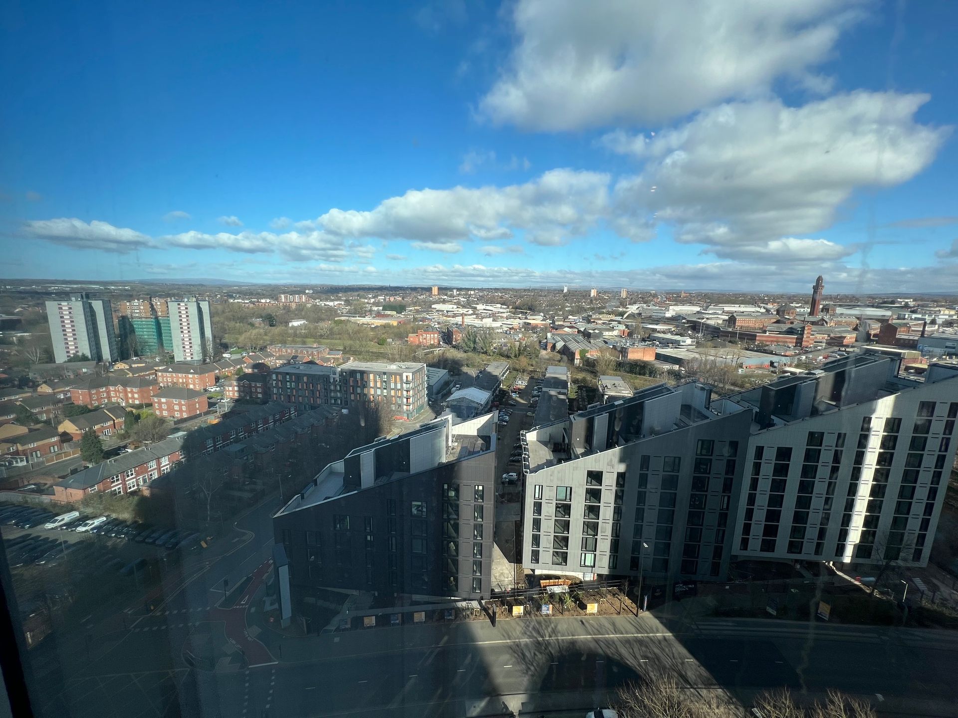 Cityscape view with buildings under a blue sky, some clouds.