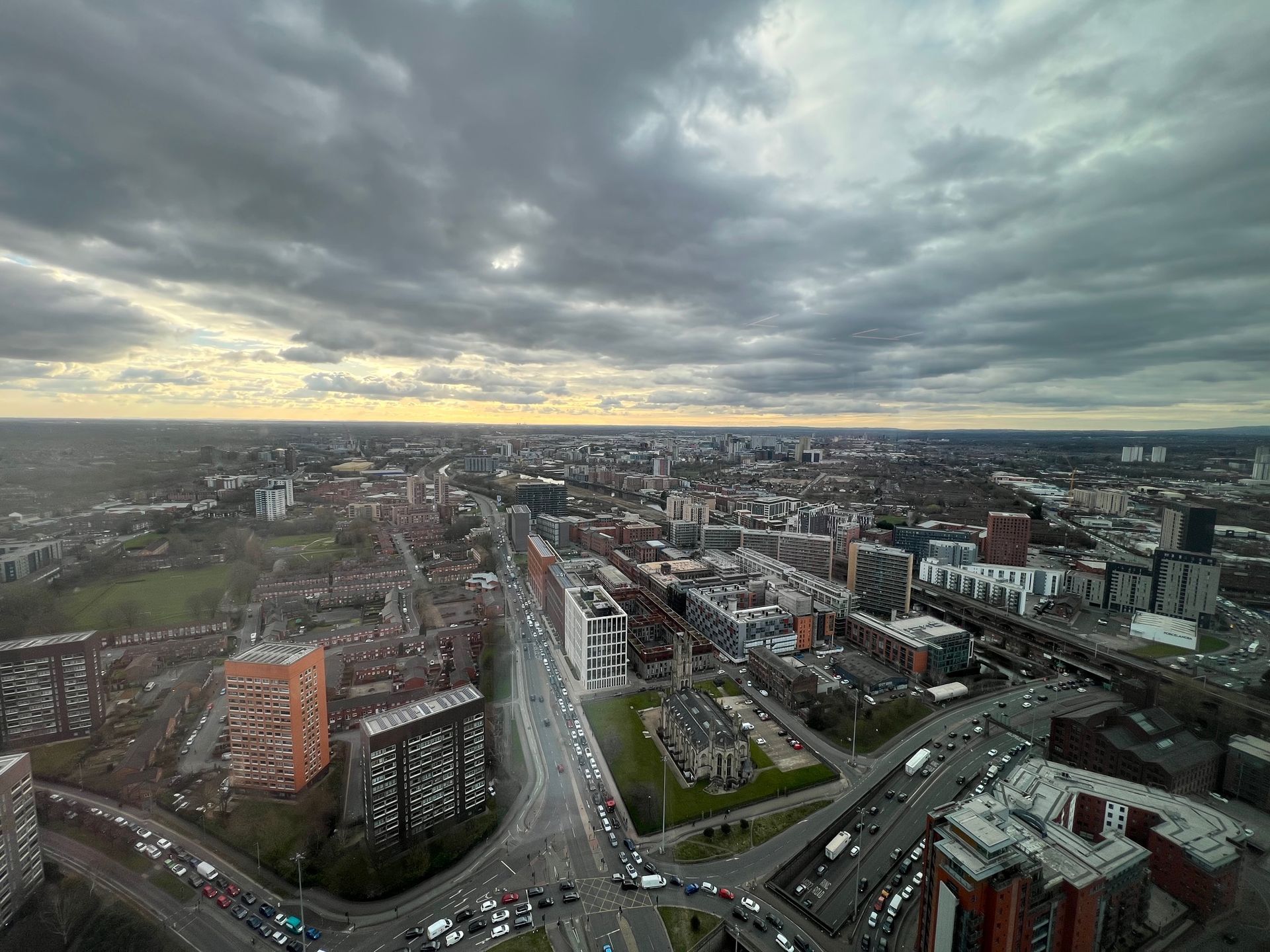 City skyline under a cloudy sky. Roads and buildings fill the view.