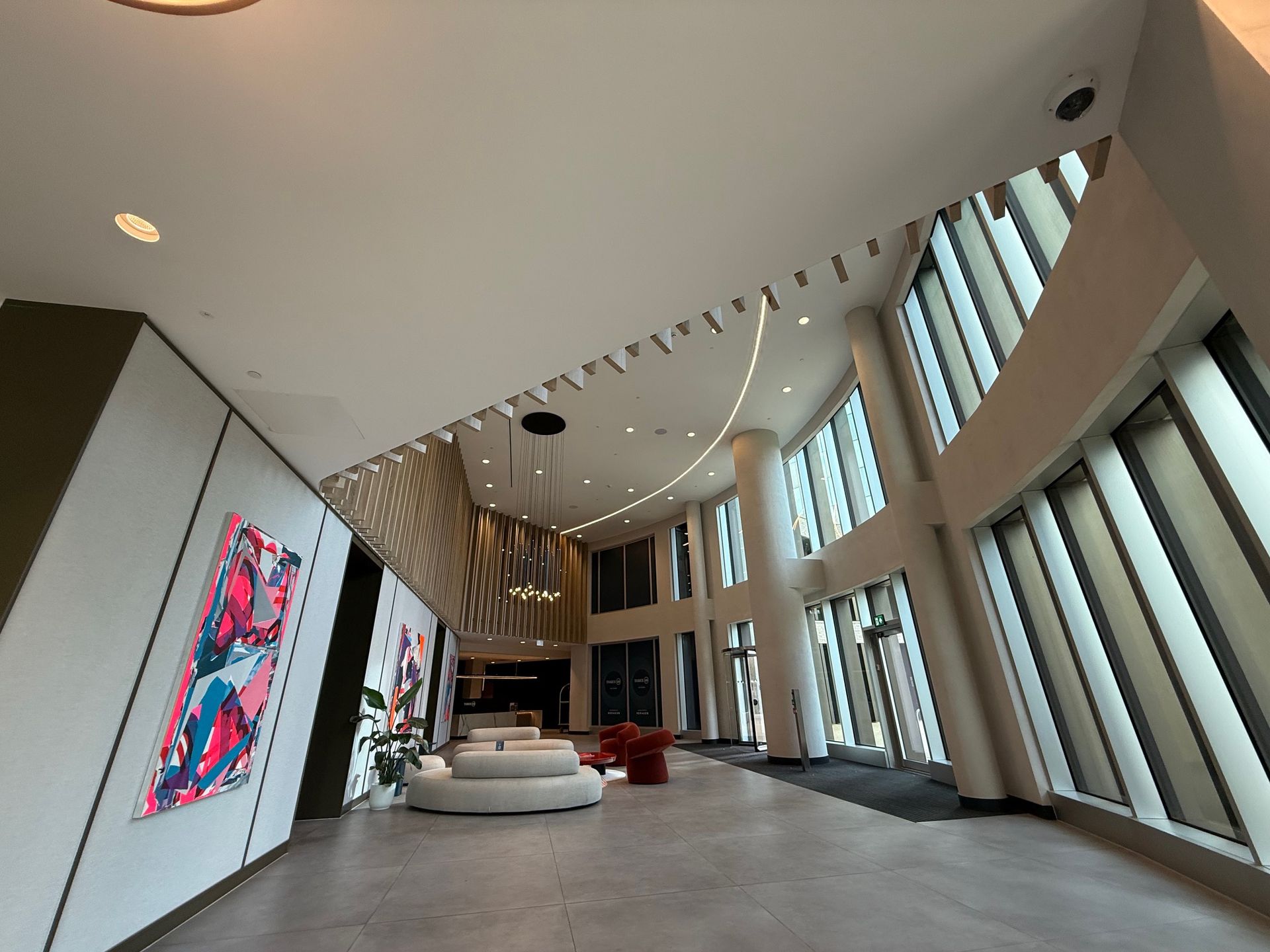 Modern lobby with large windows, art, seating, and a decorative ceiling.