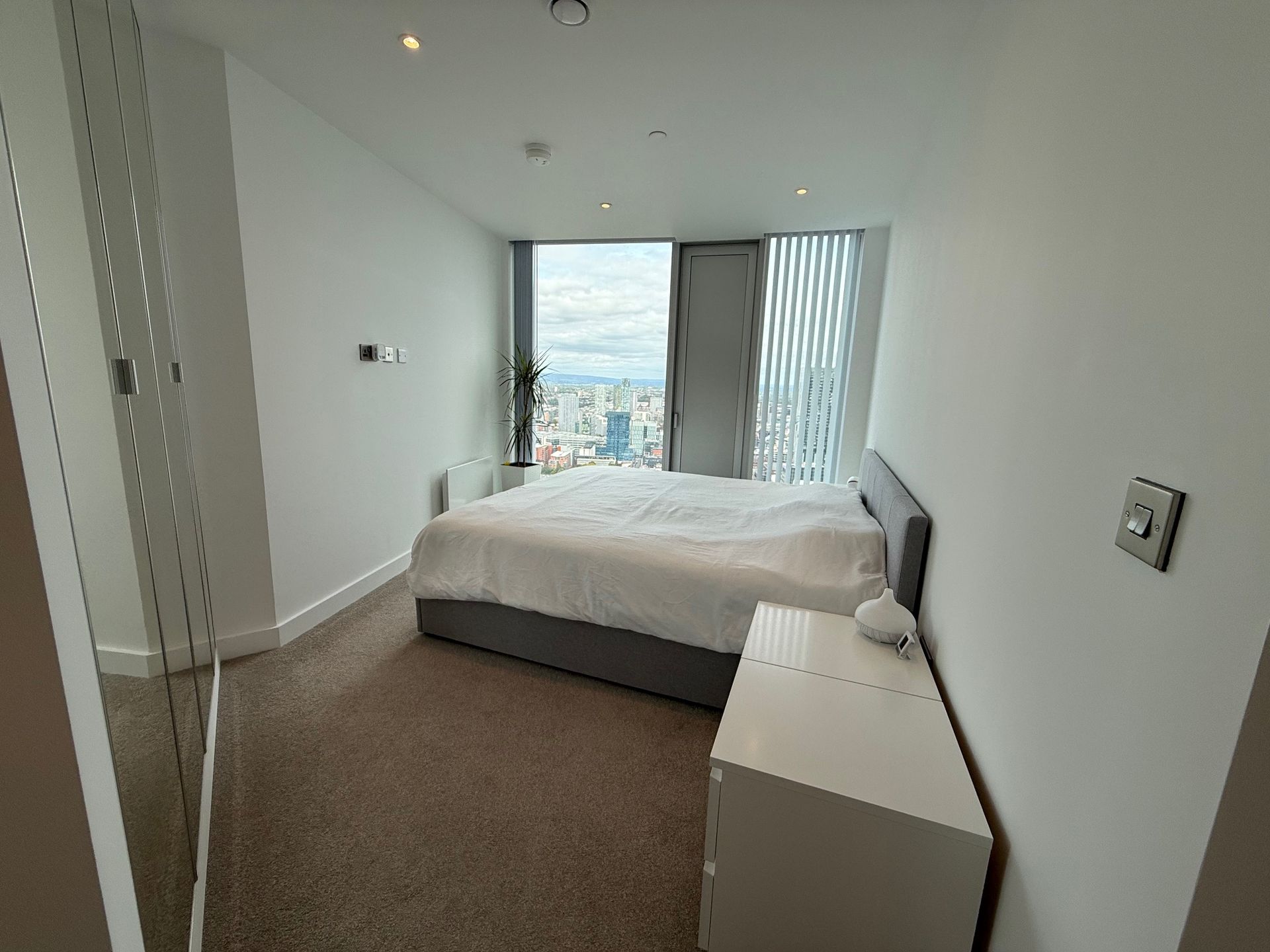 Bedroom with bed, nightstand, and window with city view.