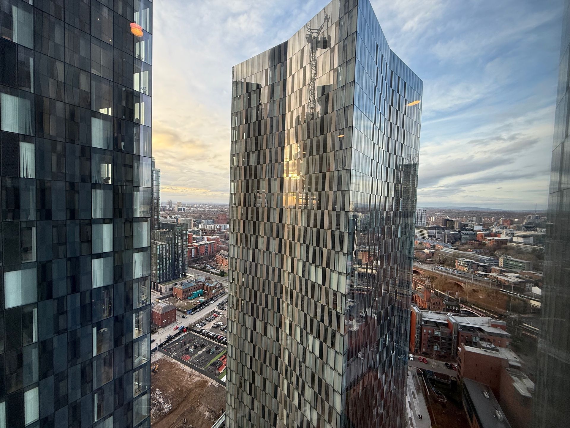 Two modern glass skyscrapers in a cityscape on a cloudy day.