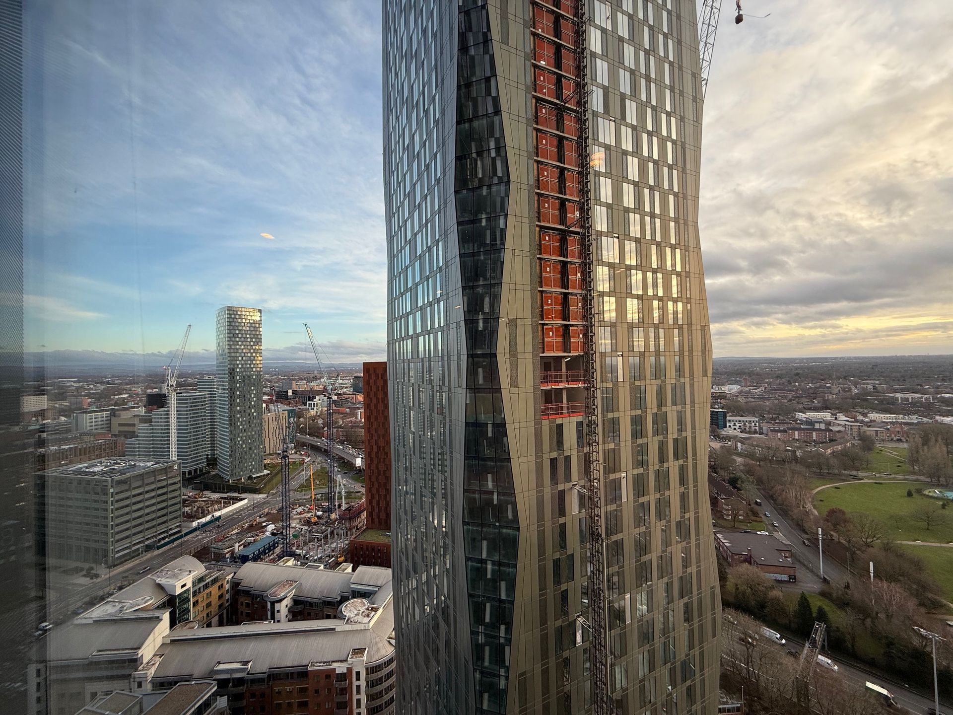 High-rise buildings in an urban setting under a cloudy sky. One has exposed construction.