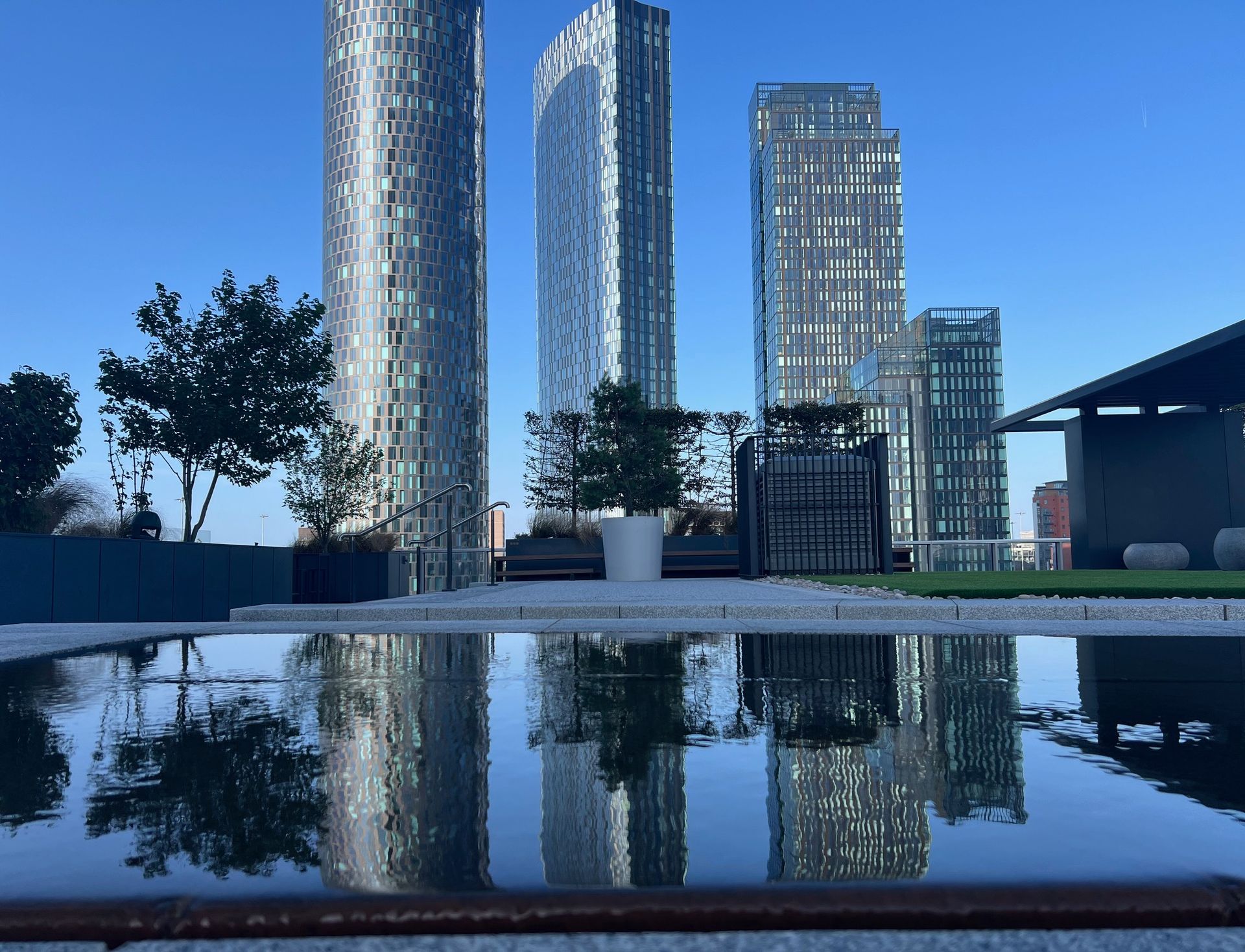 Modern skyscrapers reflected in a calm pool of water on a sunny day.