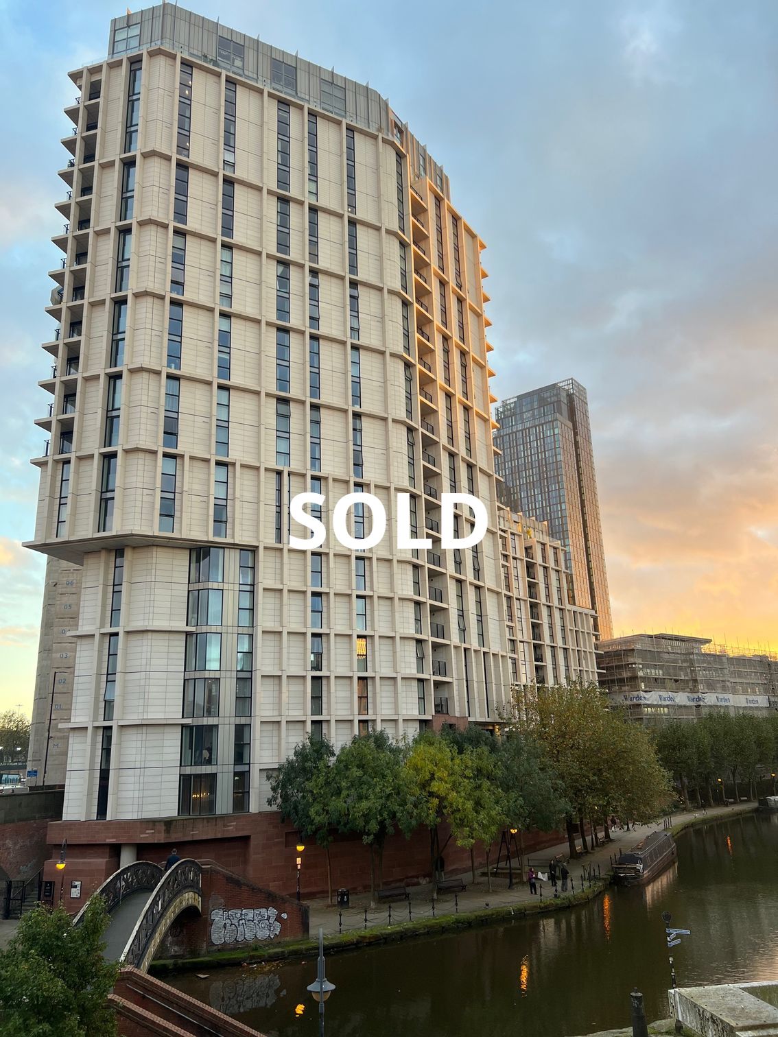 Two tall apartment buildings next to a canal; 