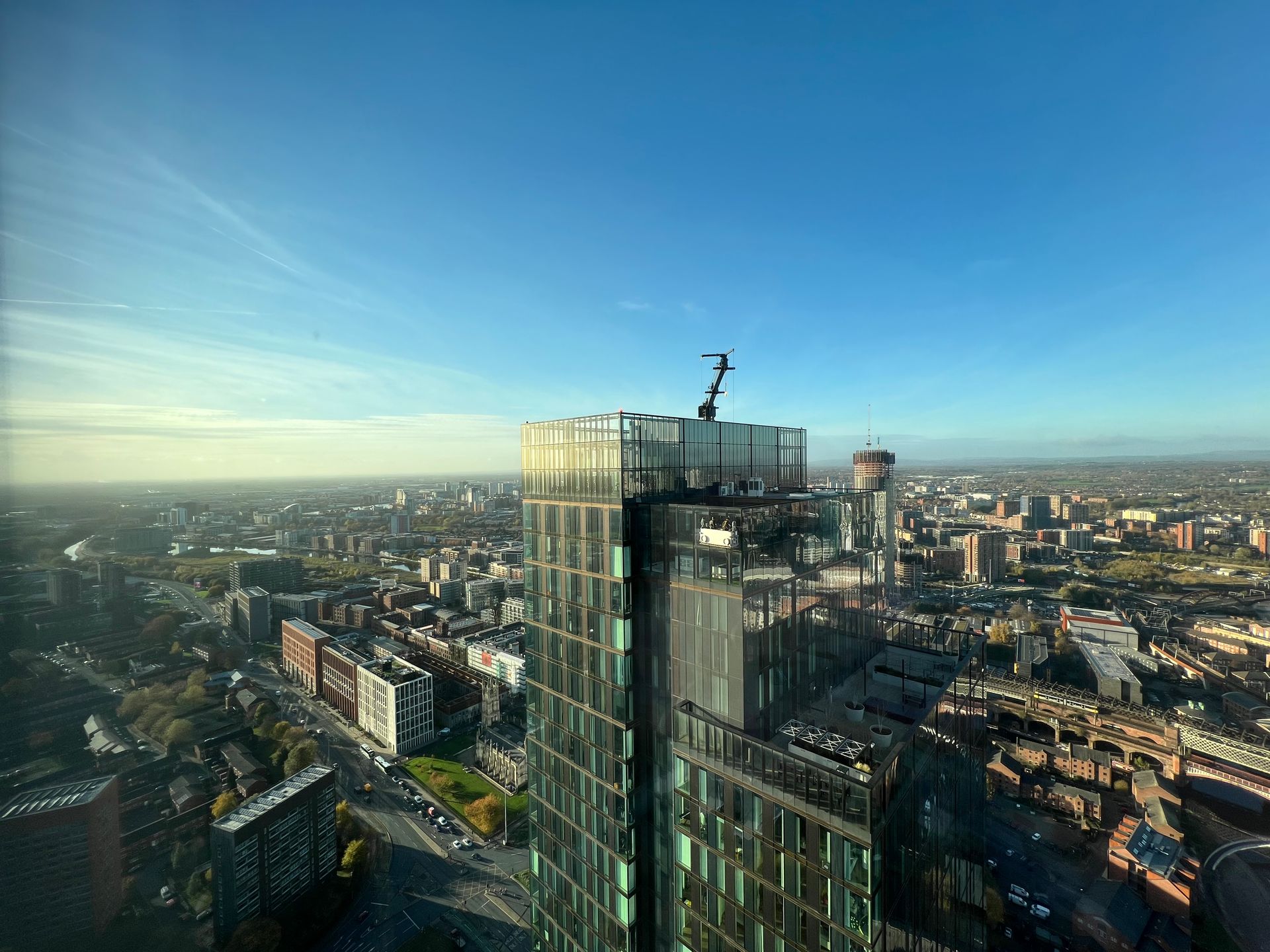 High-angle view of a tall modern skyscraper overlooking a city on a clear, sunny day.