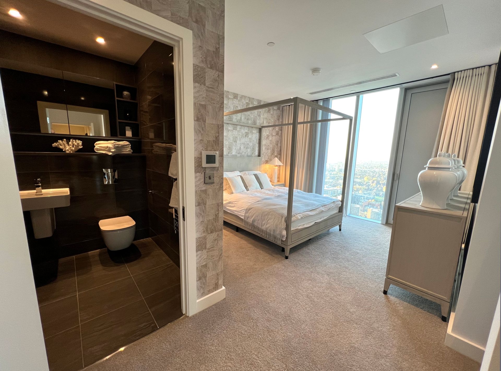 Bedroom with a four-poster bed and en-suite bathroom. Large windows offer a city view.