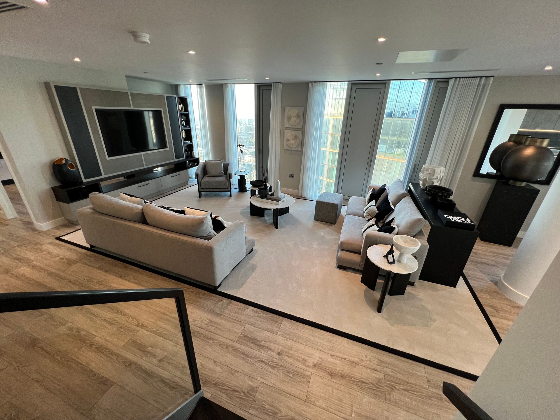 Luxurious living room with beige furniture, black accents, and large windows.