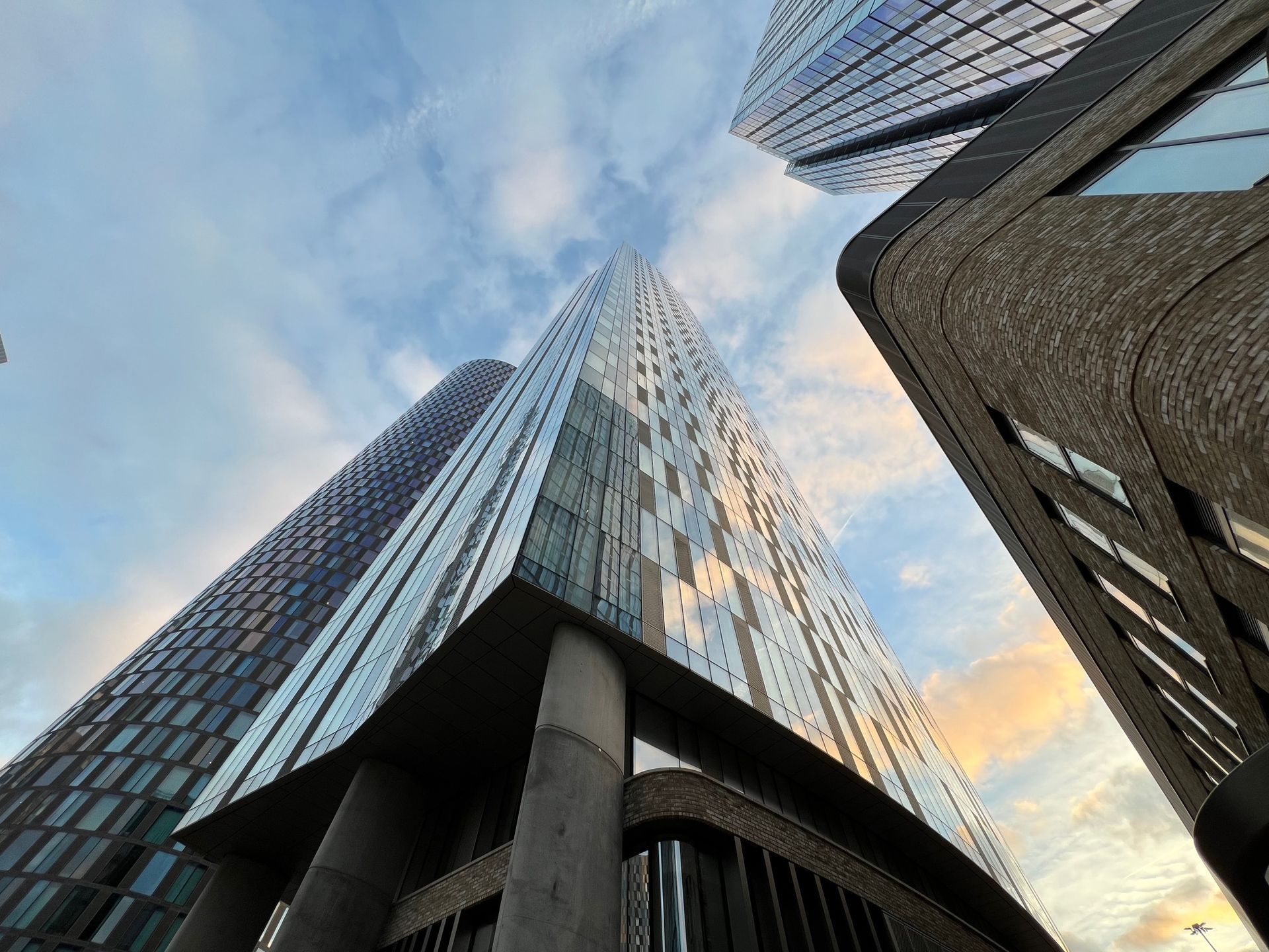 Skyscrapers against a cloudy sky, viewed from a low angle.